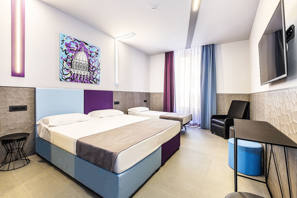A modern hotel room with two beds, a desk, a chair, a TV, and a painting on the wall.