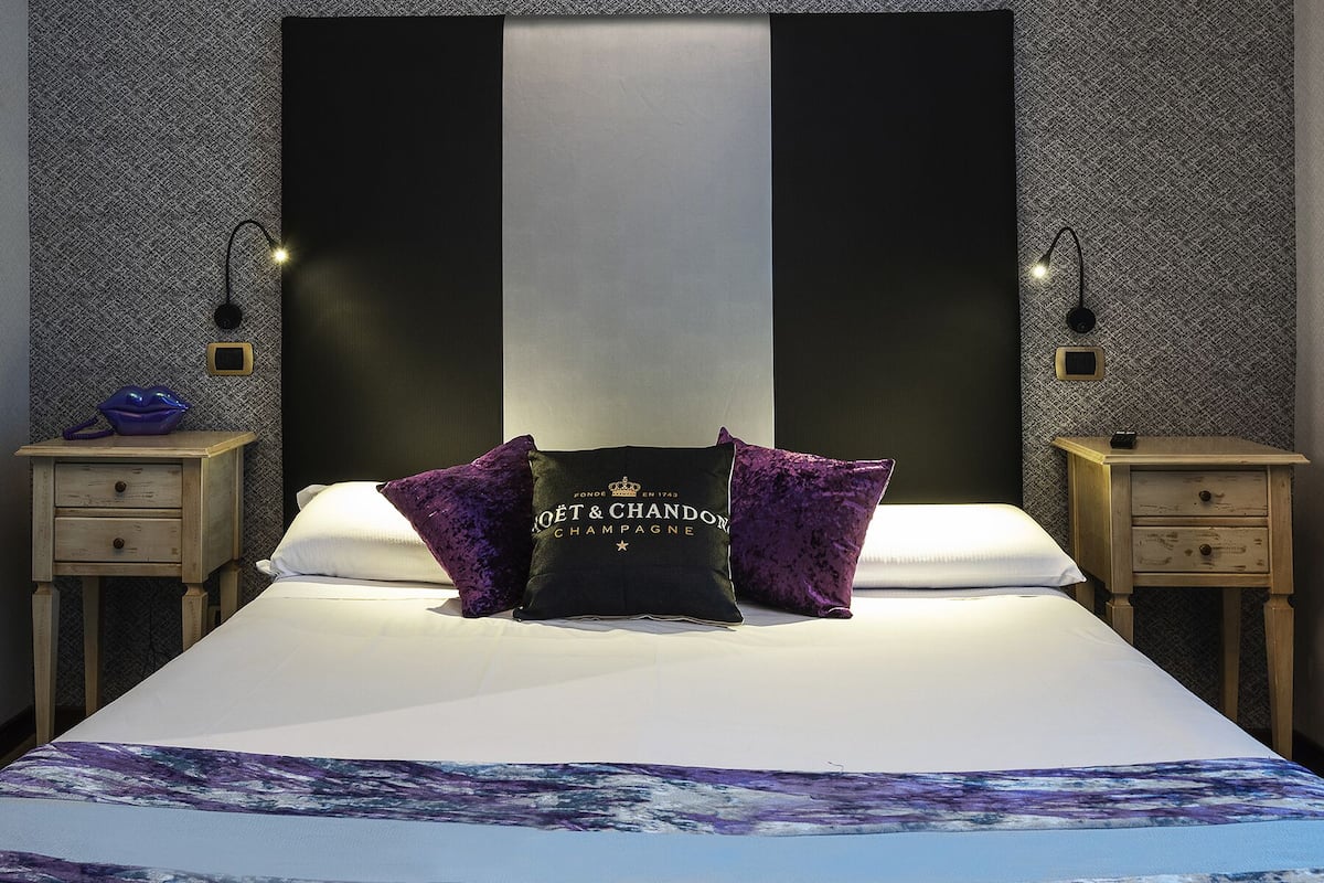 A bedroom with a large bed, two nightstands, and a headboard with a logo.