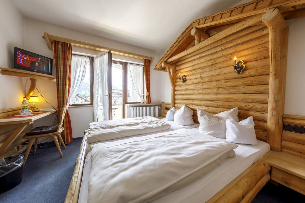 Een houten kamer in chaletstijl met twee bedden, een televisie, een bureau en een stoel.