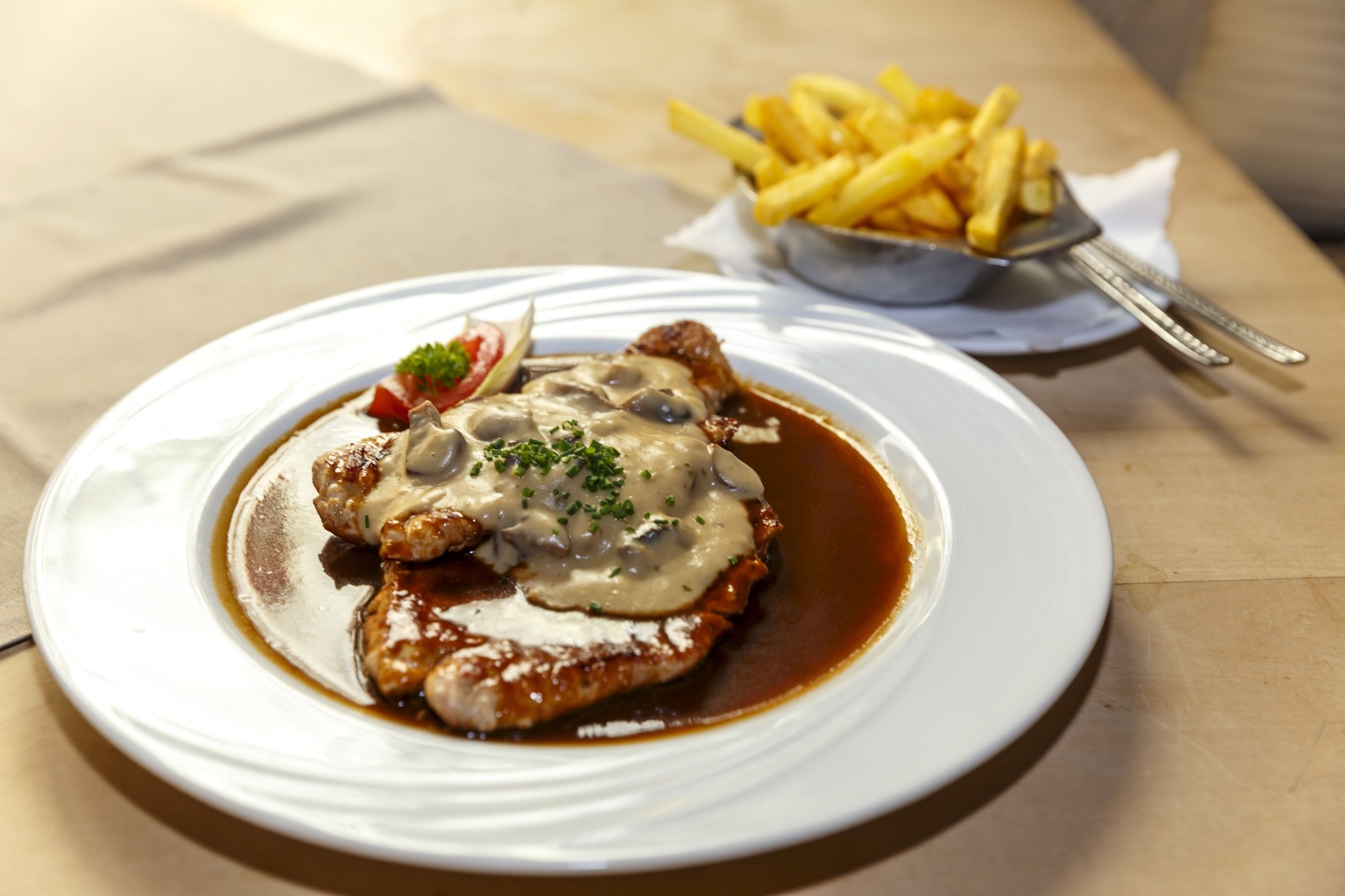 A plate of food with a white plate, a fork, and a small bowl of fries.