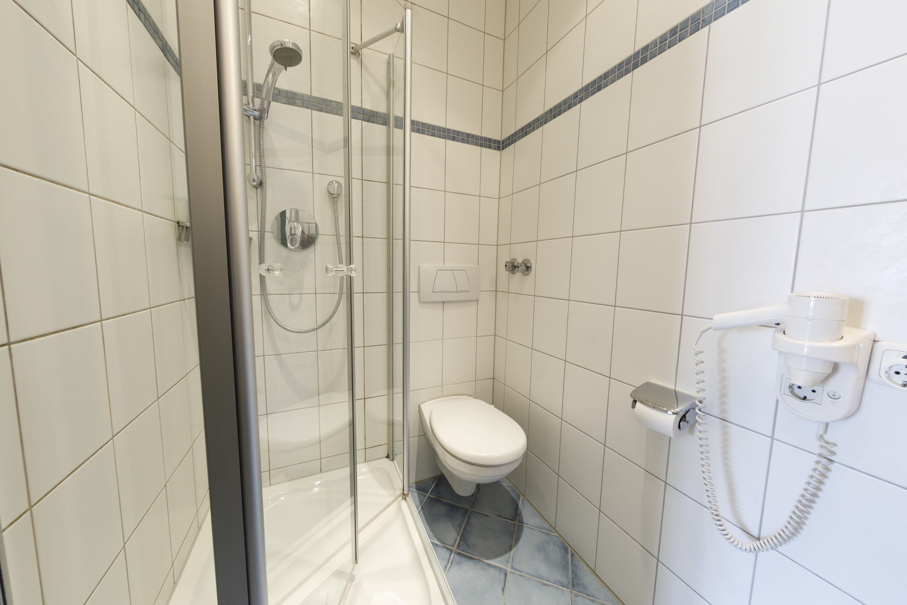 Een badkamer met een douche met glazen wand, een toilet en een telefoon.