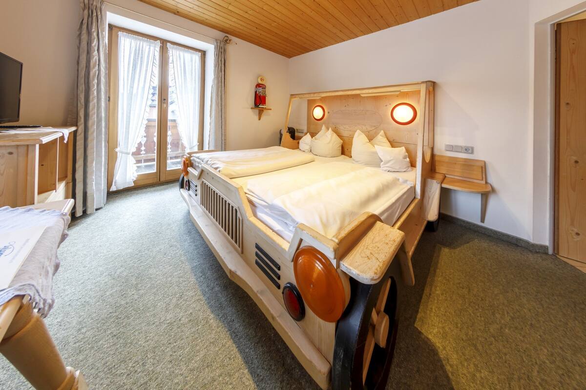 Een hotelkamer met een houten bed, een televisie, een tafeltje en een raam met gordijnen.