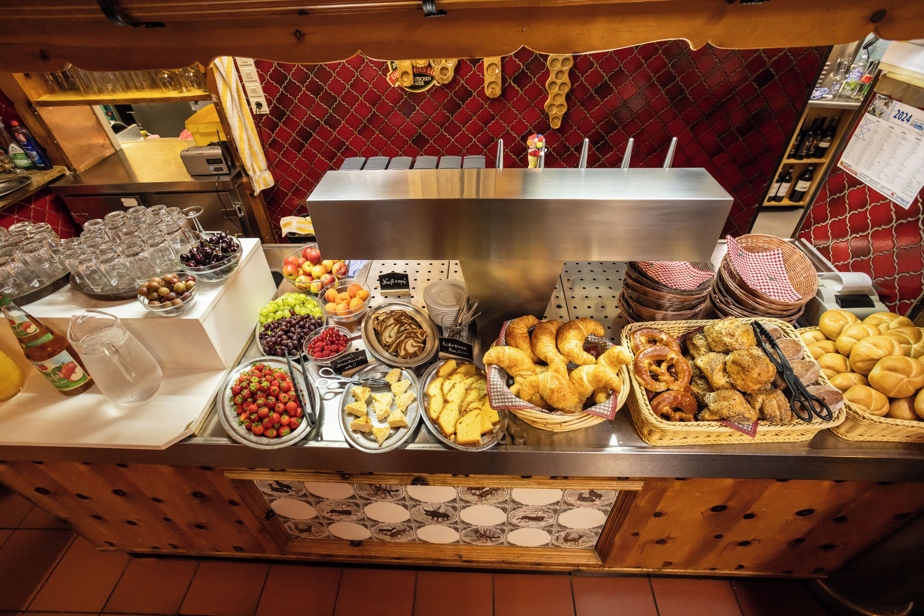 A buffet with various food items including fruits, pastries, and bread.