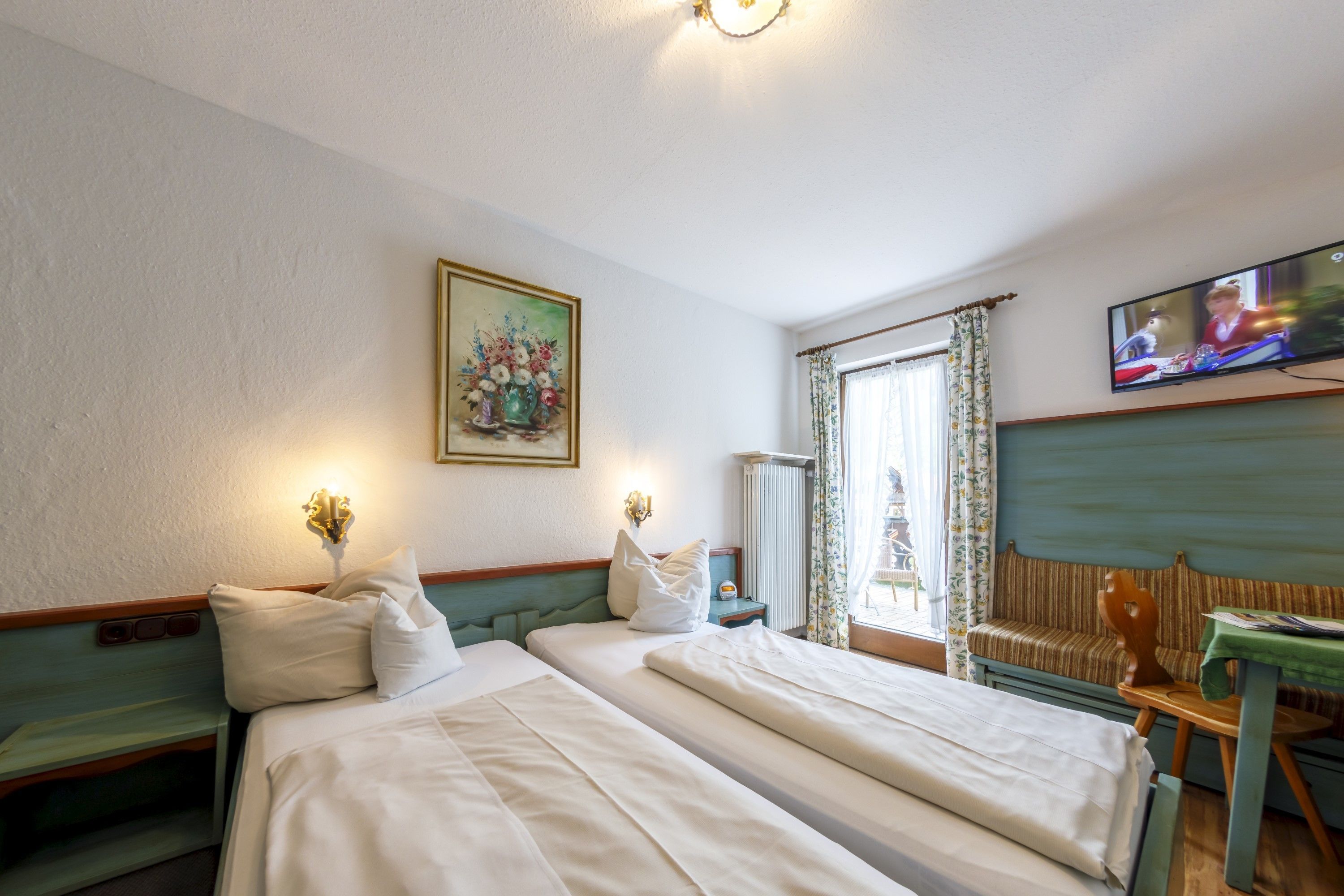 A hotel room with two beds, a painting, a television, and a window with curtains.