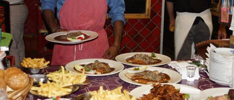 A restaurant table with various dishes, including plates of food, a basket of bread rolls, and a bowl of fries.