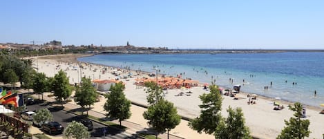 Una playa con sombrillas, gente y cielo despejado.