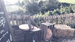 Un espace extérieur rustique aménagé avec une clôture en bois, une table ronde et une botte de foin.