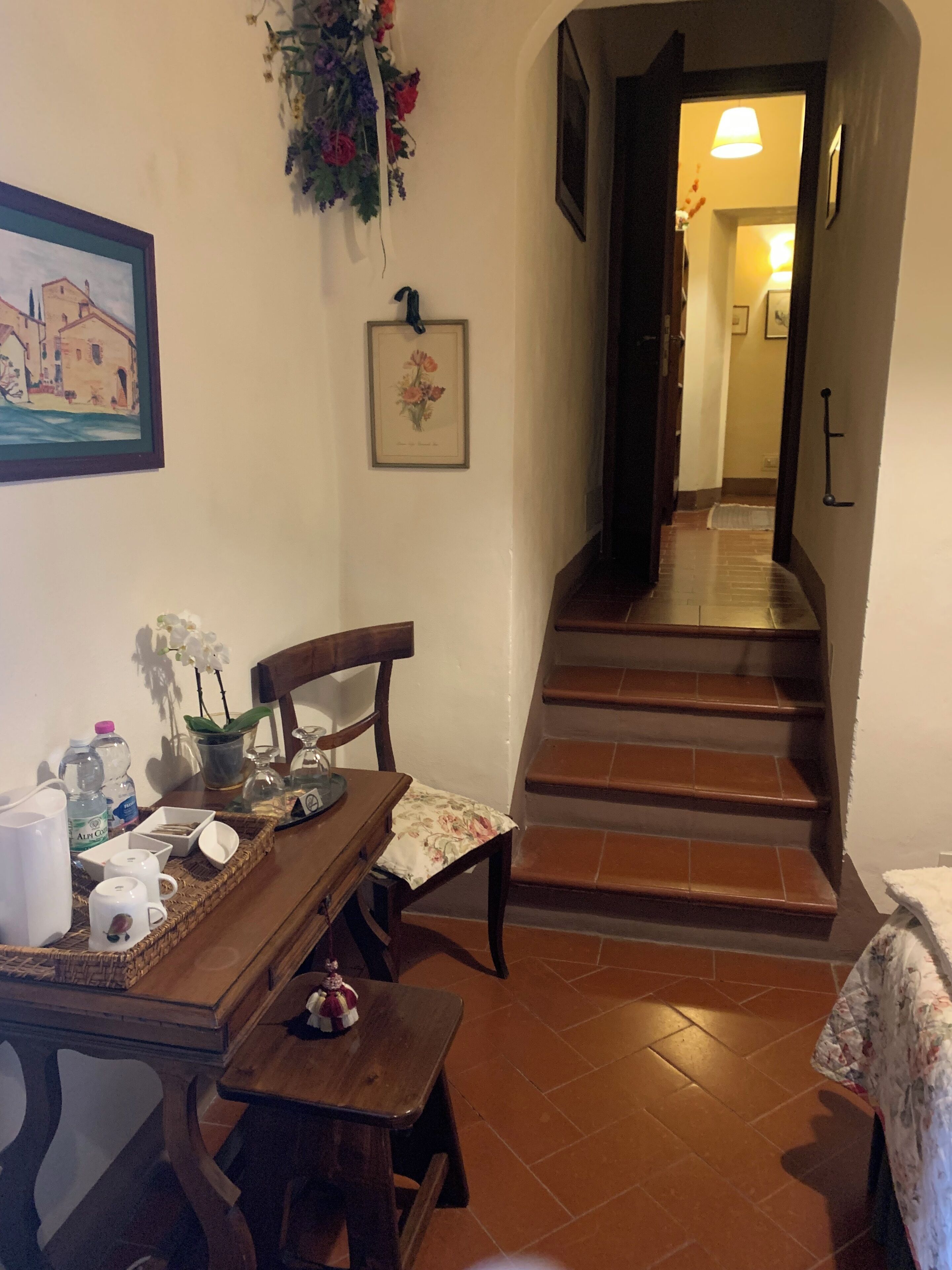 A dining area with a wooden table, chairs, and a staircase leading to another room.