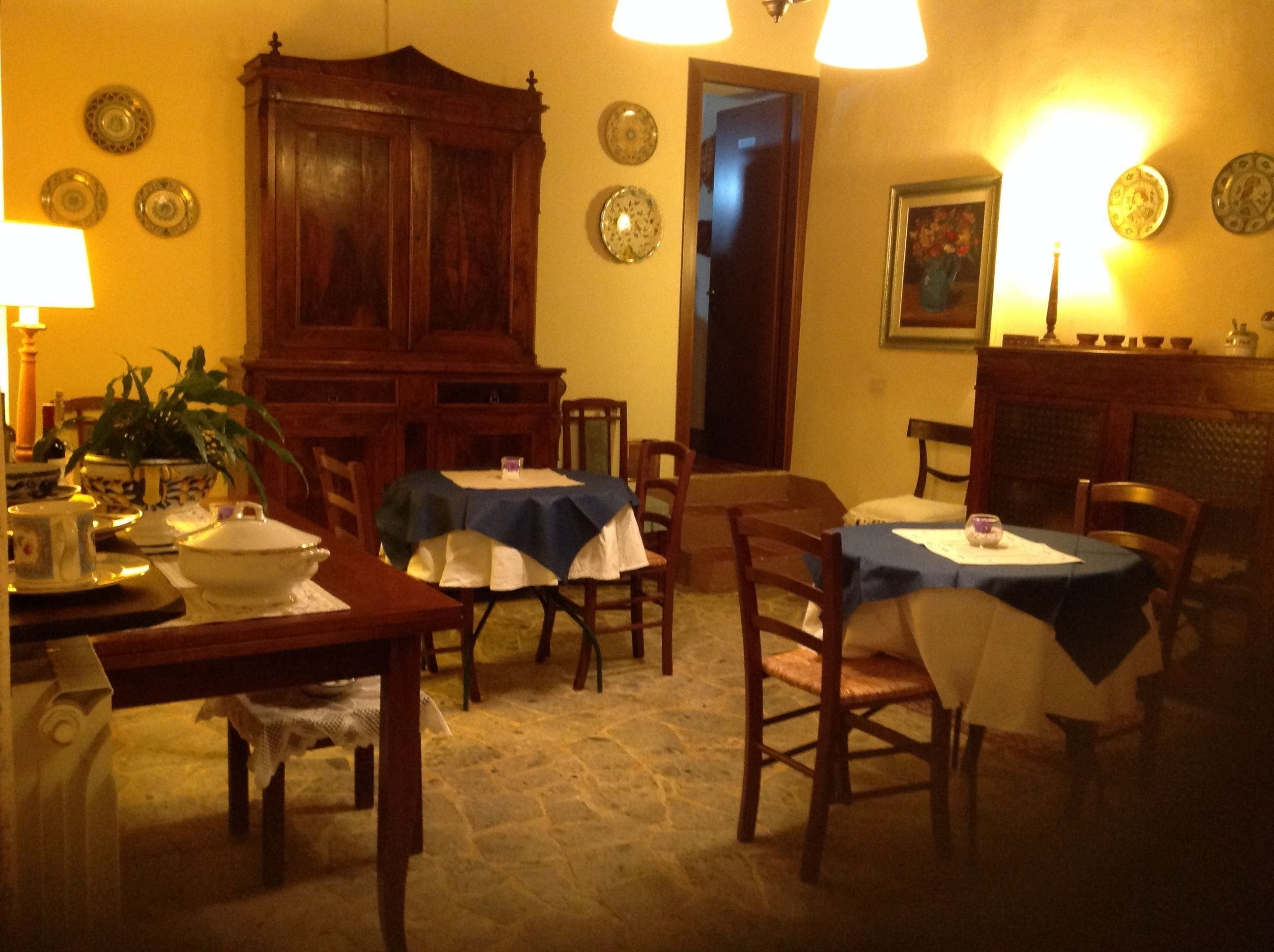 A dining area with two tables, chairs, a wooden cabinet, and wall decorations.