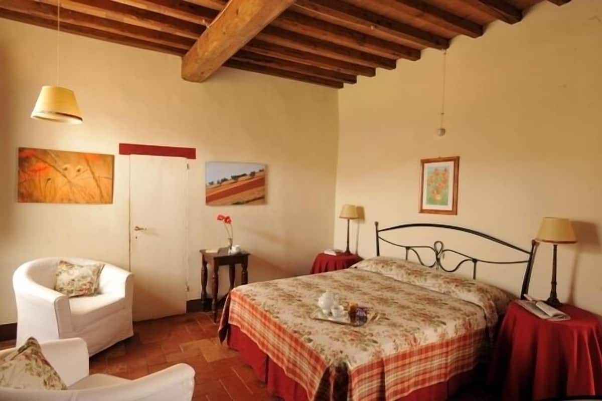 A bedroom with a bed, two bedside tables, a chair, and a lamp.
