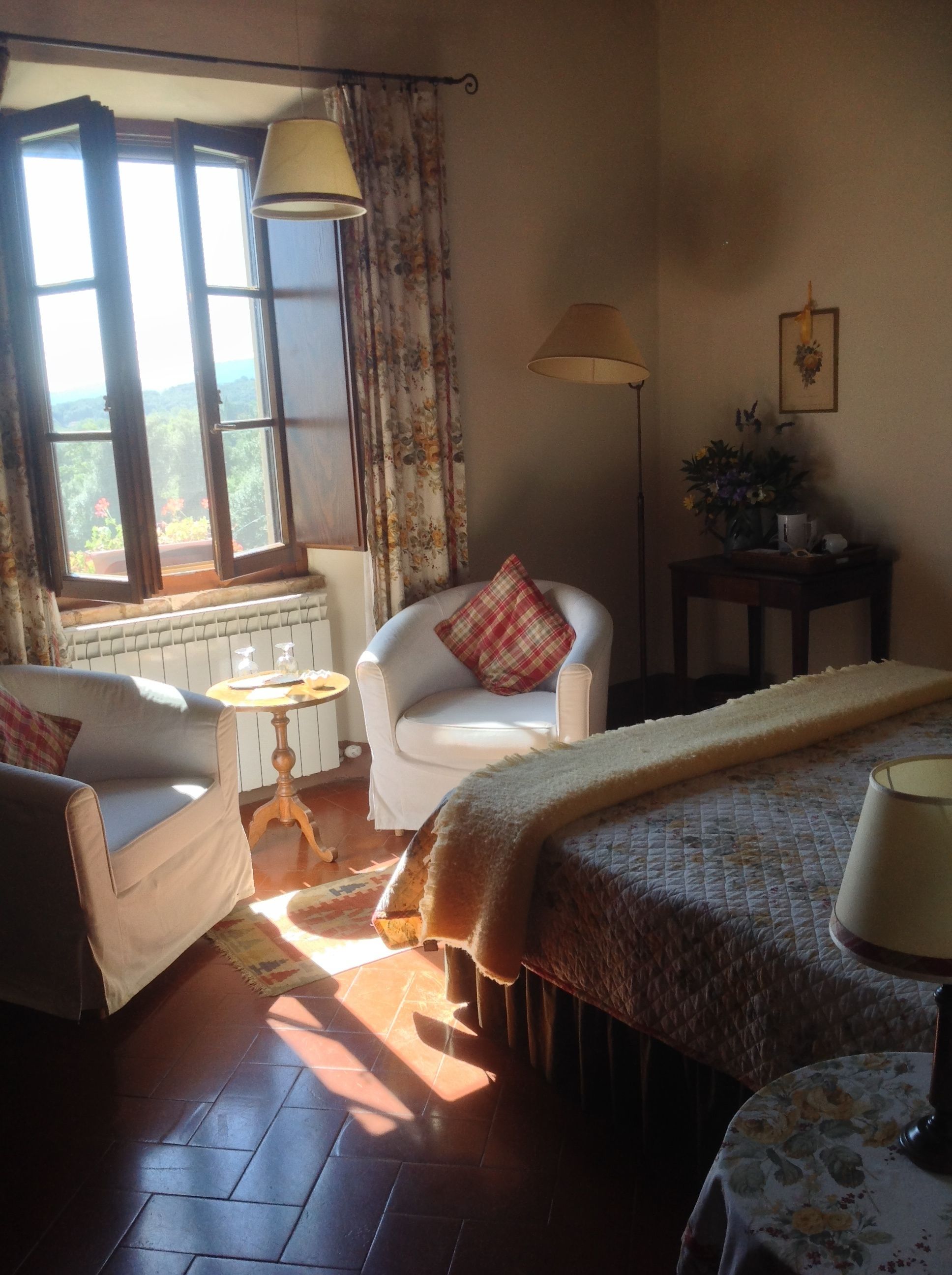 Ein gemütliches Zimmer mit Bett, Stuhl, Tisch und einem Fenster mit Vorhängen.