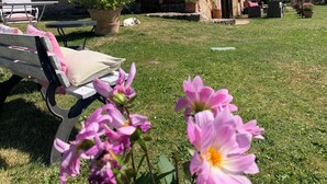 A stone building with a garden, a bench, and a covered area. - La Canonica di San Michele (Monteriggioni)