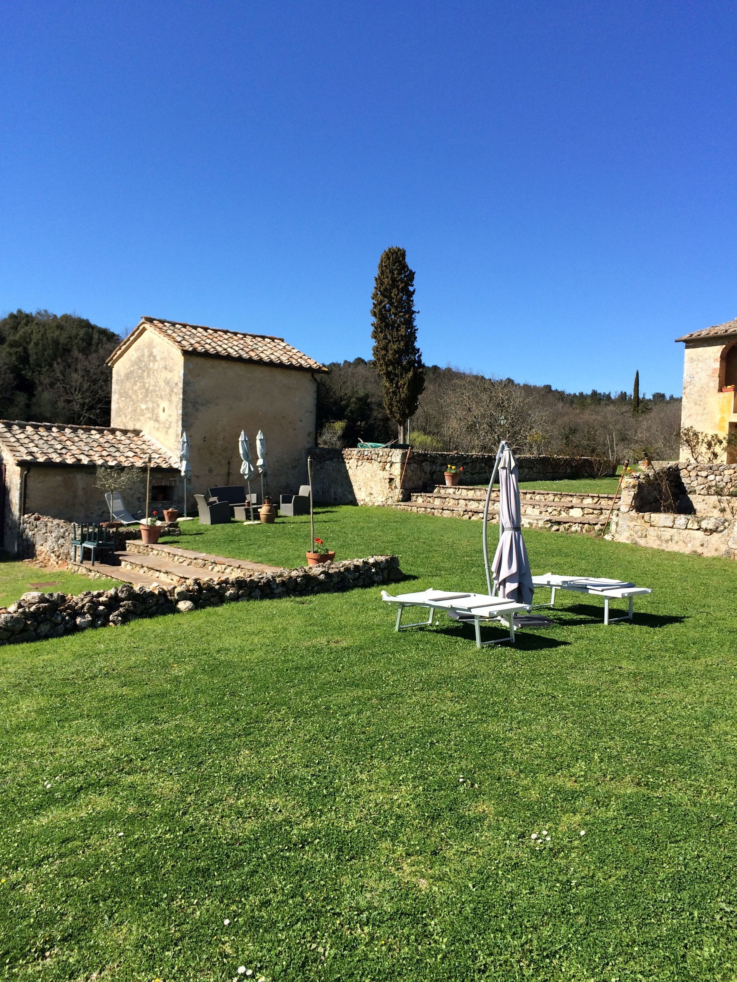 A well-maintained outdoor area with a stone wall, a grassy lawn, and a few lounge chairs.