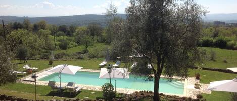 Una piscina al aire libre de temporada, sombrillas