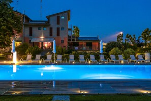 Ein Schwimmbecken mit Liegestühlen und Sonnenschirmen, ein Gebäude mit Restaurant sowie ein klarer Himmel.