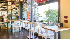 Een restaurant met een stenen muur, houten tafels en witte stoelen.