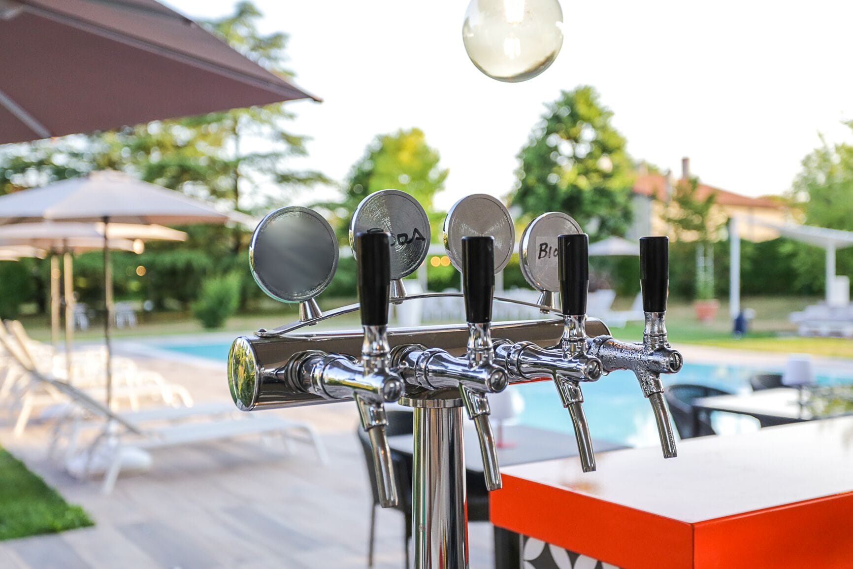 A row of beer taps with a pool in the background.