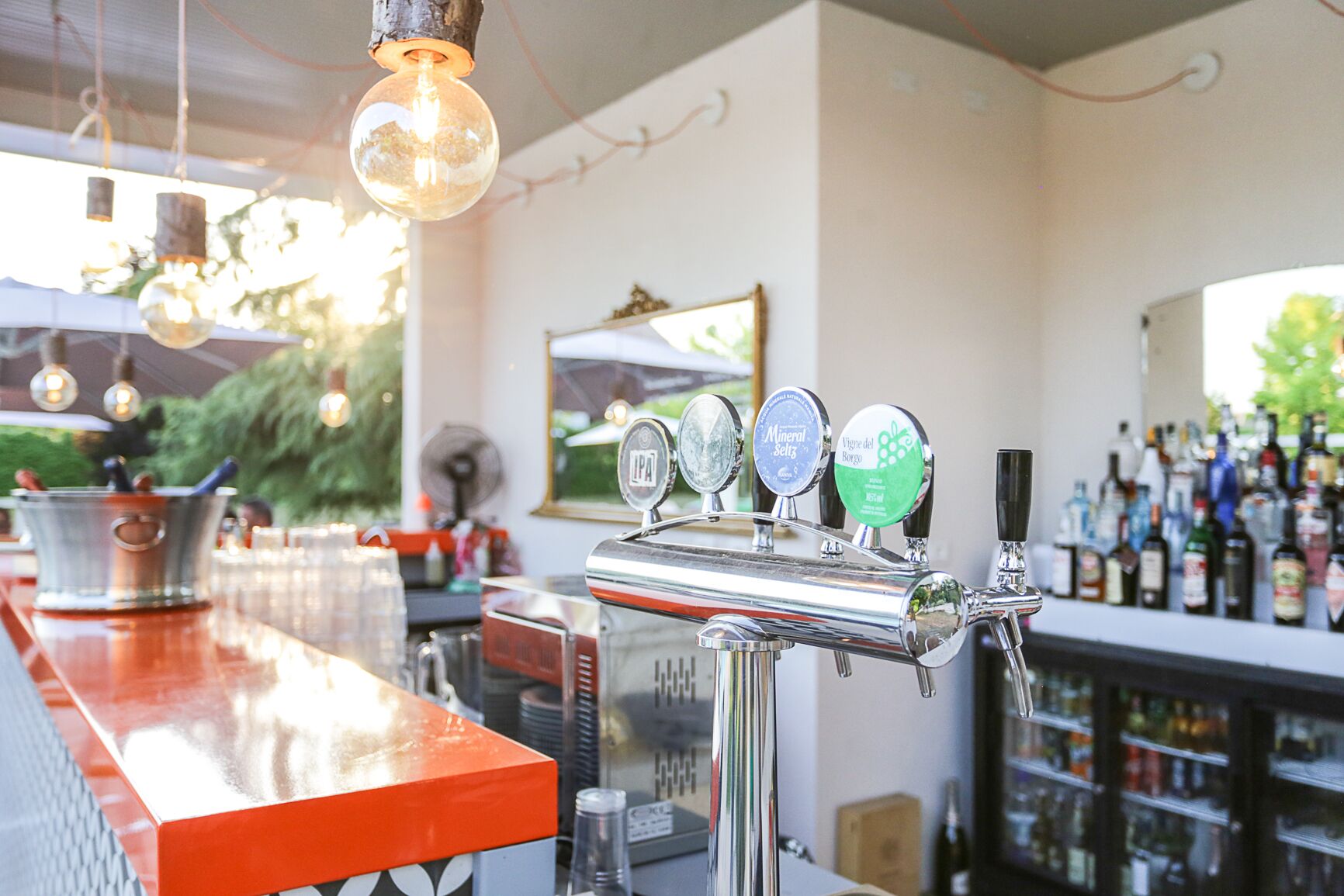 A bar area with a beer tap and a variety of bottles in the background.