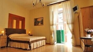 A bedroom with a bed, bedside tables, a painting, a television, and a view of the outside. - Domus Gemi (Naples)