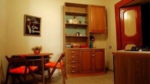 A compact kitchen with a dining table, chairs, wooden cabinets, and a small countertop. - Domus Gemi (Naples)