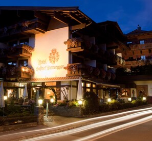 A hotel with a prominent sign, outdoor seating, and flower boxes on balconies. - Hotel Gasthof Mitteregger (Kaprun)