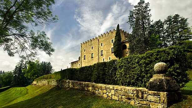 Un château de pierre historique, doté d’un mur d’enceinte élevé, d’une pelouse bien entretenue et d’une végétation luxuriante tout autour.