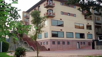 A multi-story building with balconies, large windows, and a staircase leading to the entrance.