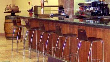 Una zona de bar con taburetes y una barra, una máquina de café y un barril de madera grande.