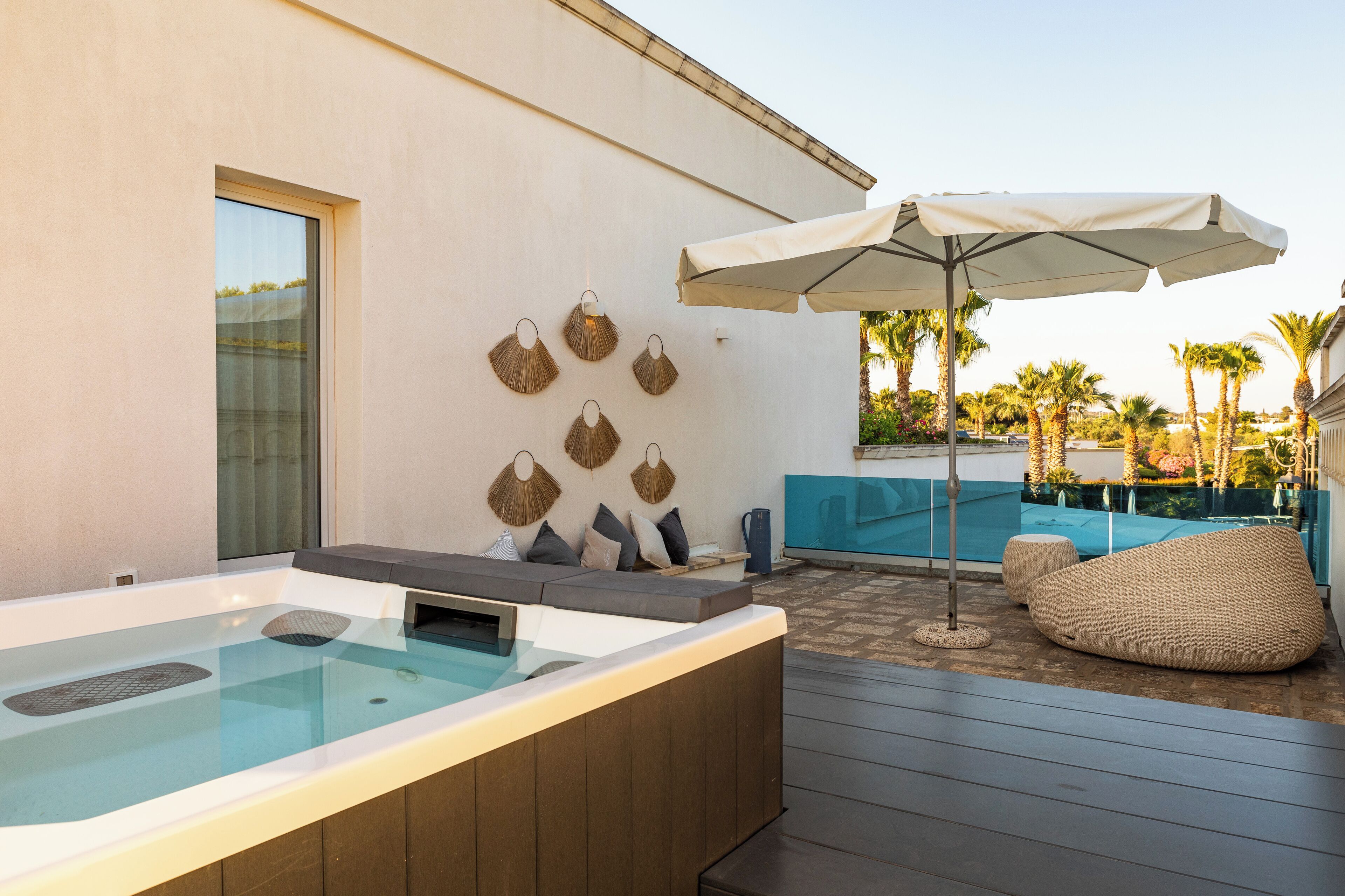 A hot tub area with a wooden deck, a seating area with cushions, and a wall-mounted fan.