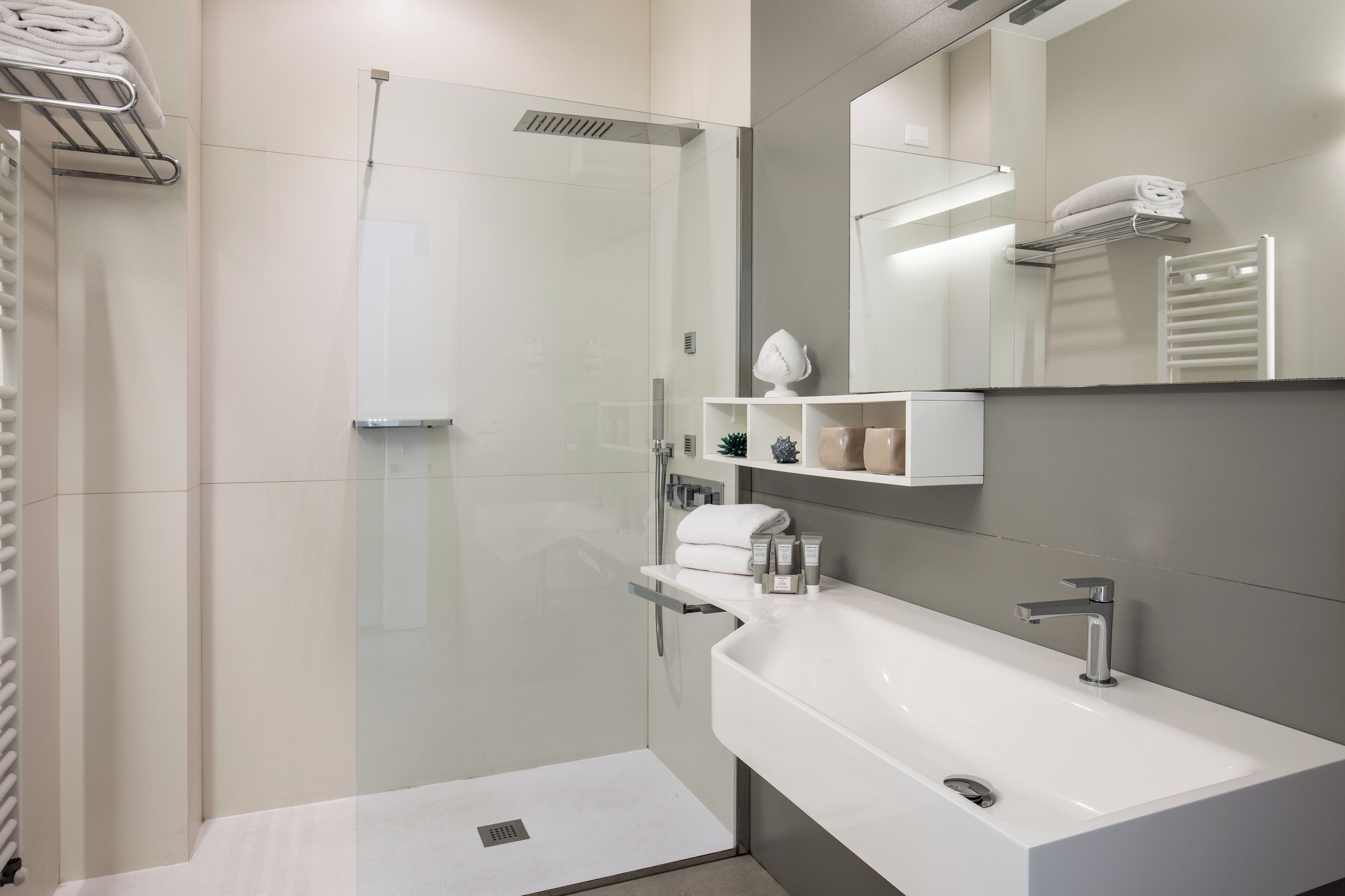 A modern bathroom with a glass-enclosed shower, a white sink, and a large mirror.