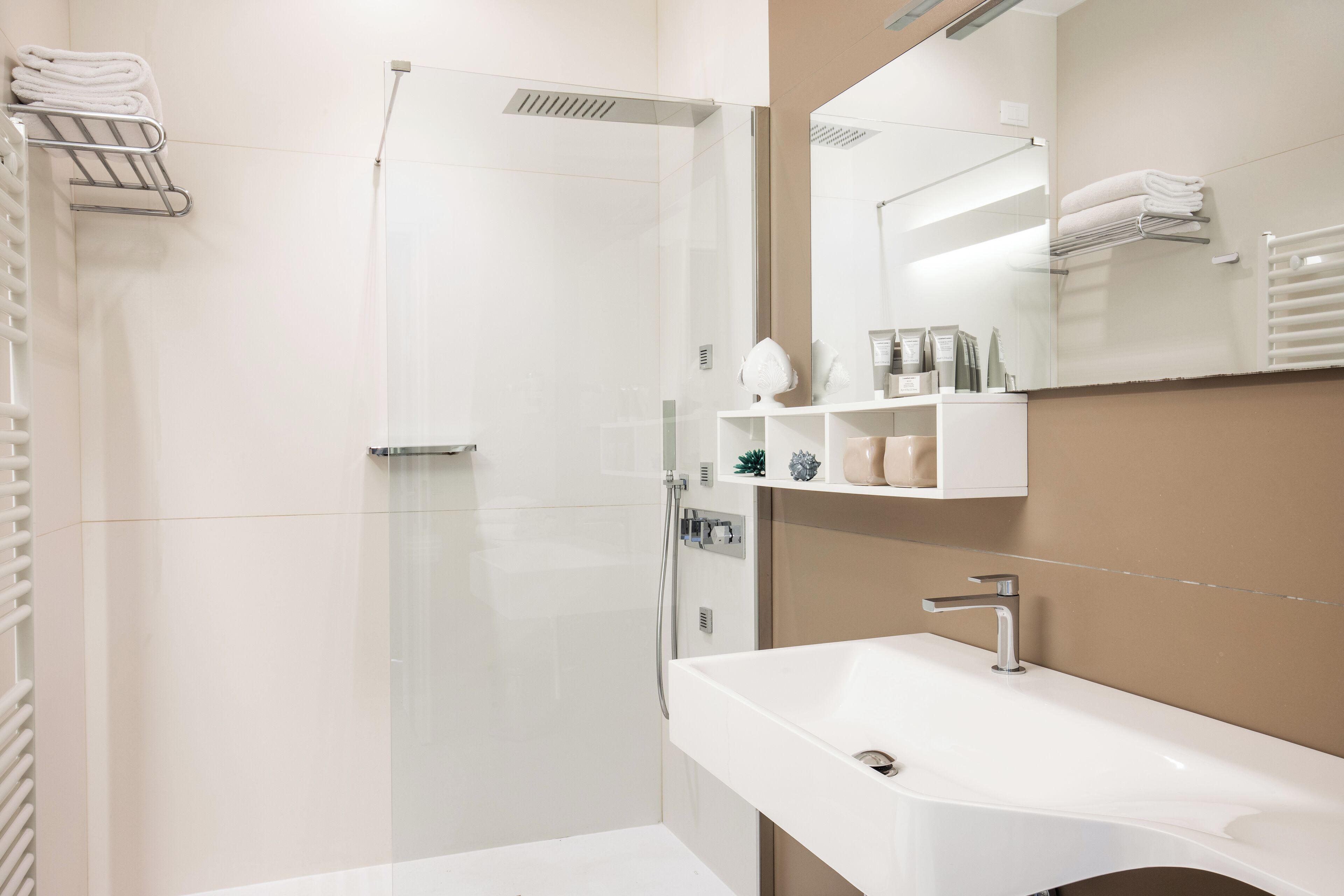 Un baño moderno con cabina de ducha de vidrio, un lavamanos blanco y un espejo encima.