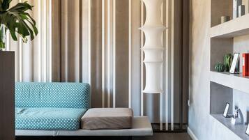 A modern living room with a sofa, a tall white light fixture, and a plant.
