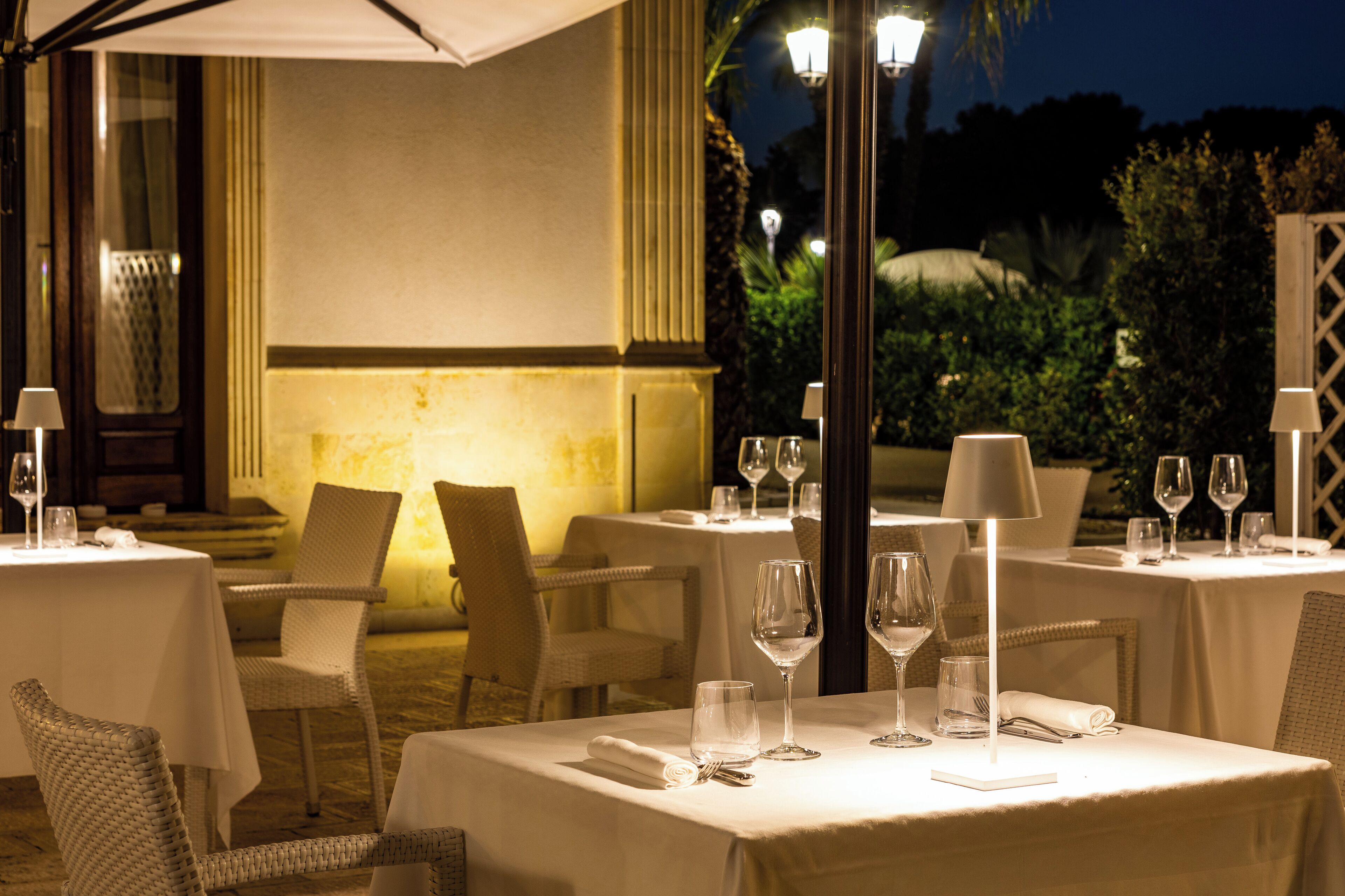 Un restaurant amb terrassa, taules cobertes amb estovells blancs i copes de vi.