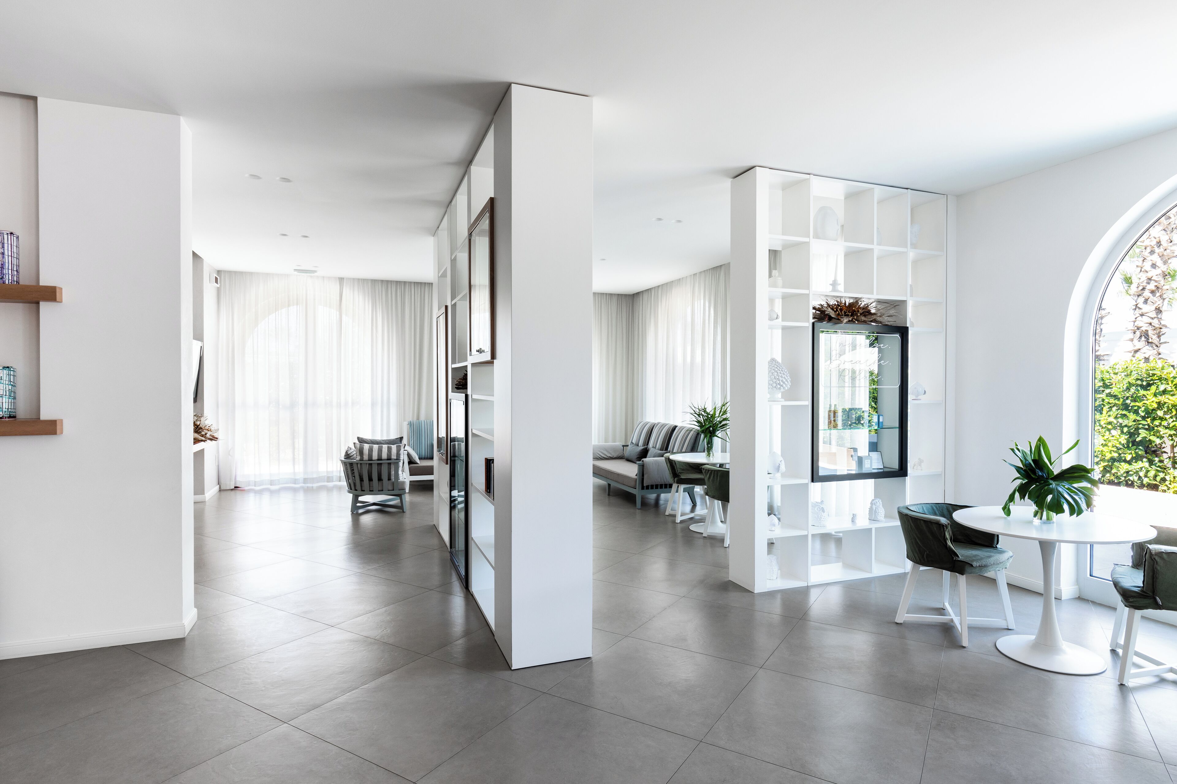 A modern living room with a dining area, large windows, and a view of greenery.