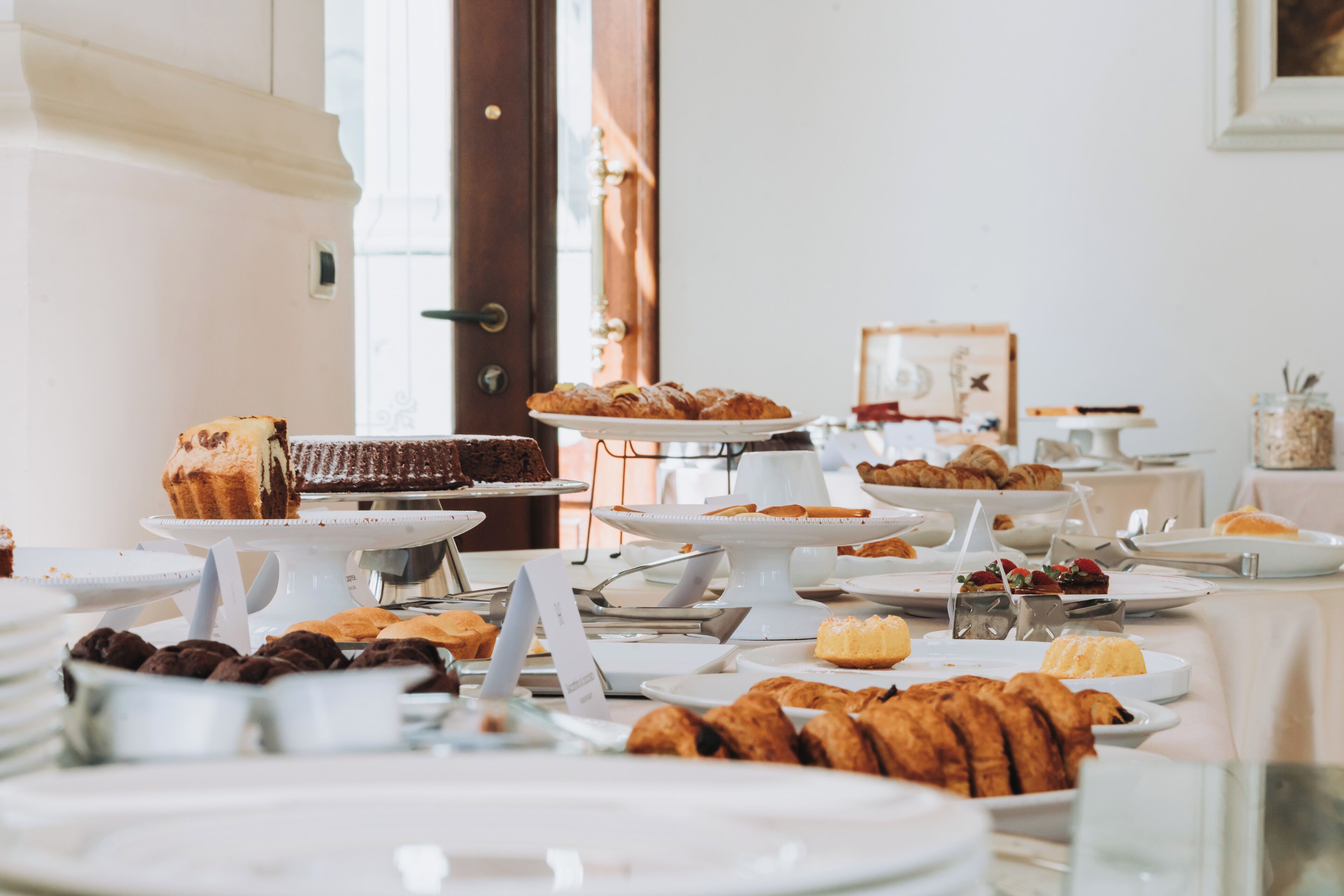 A buffet with various pastries and desserts on white serving stands.