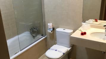 Une salle de bain comprenant des toilettes, une douche à parois de verre, un lavabo et un miroir.