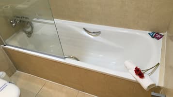 A bathroom with a bathtub, a glass shower enclosure, and a toilet.