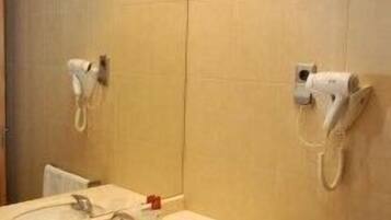 A bathroom with a sink, mirror, towel rack, and two hair dryers mounted on the wall.