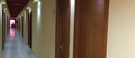 A long, narrow hotel corridor with wooden doors, numbered 101, and a tiled floor.