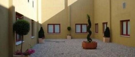Un patio con paredes amarillas, plantas en macetas y una fuente central.
