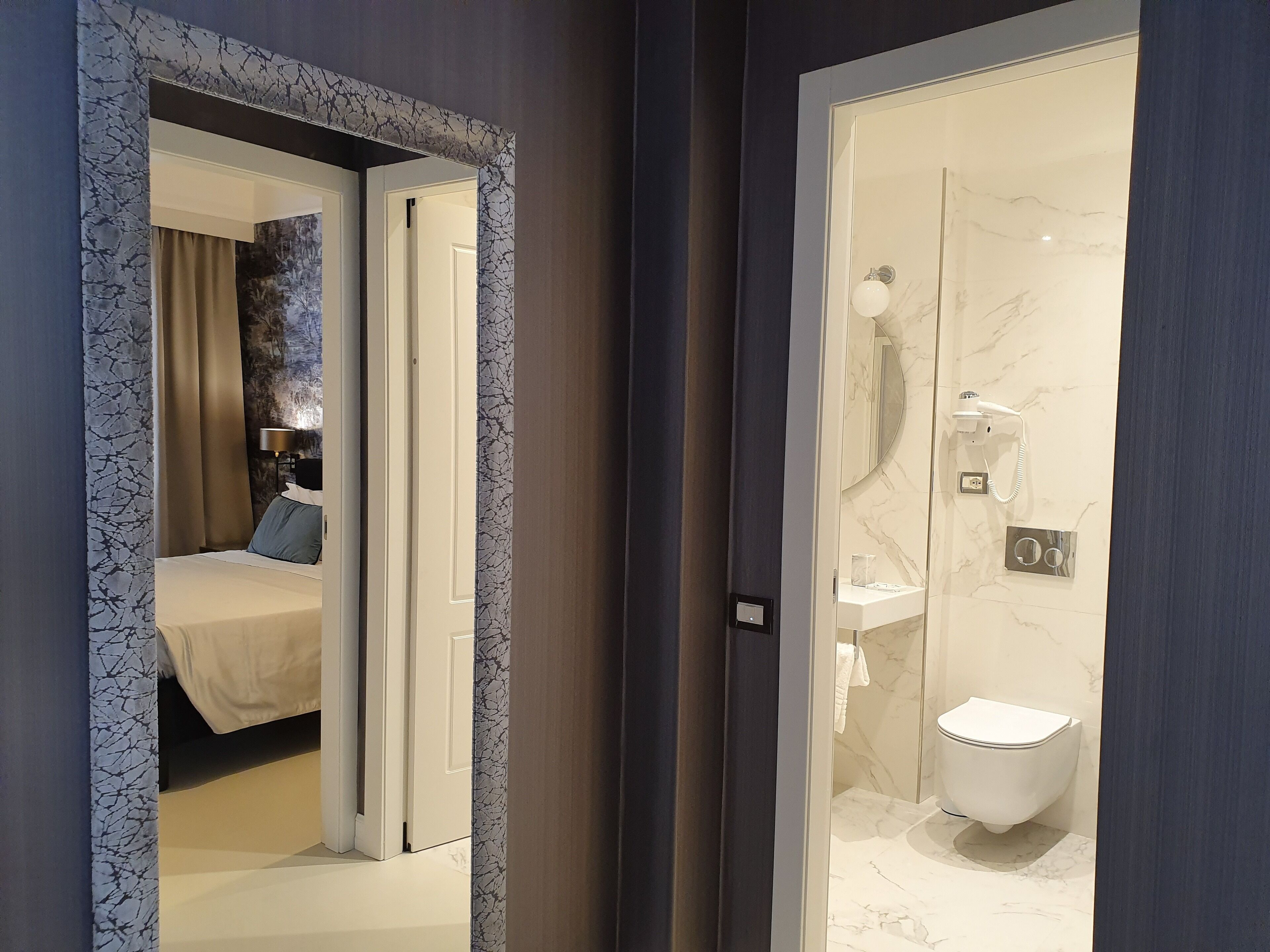 Un baño moderno con lavamanos, inodoro y cabina de ducha con paredes de vidrio de mármol.