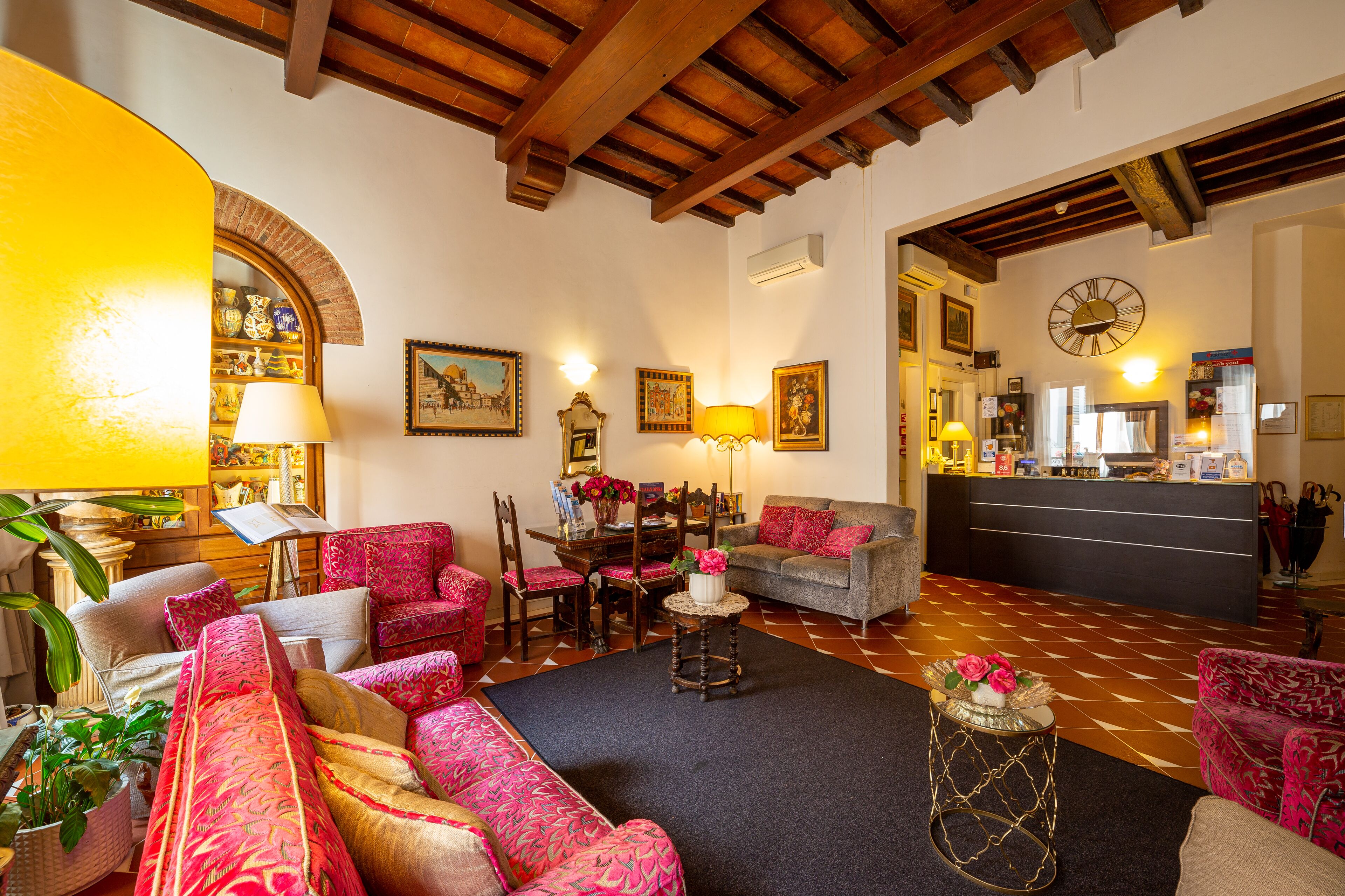 A spacious living room with a wooden ceiling, a reception desk, and a clock on the wall.