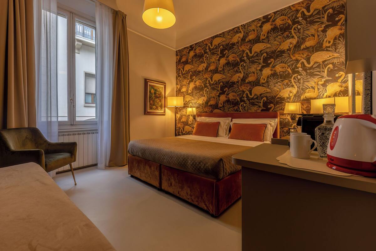 Een hotelkamer met een groot bed, een bureau met koffiezetapparaat, een stoel en een muur met een tropisch dierenprint.