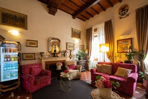 Un accogliente soggiorno con camino, divani rossi a fantasia, un frigorifero vintage Coca-Cola e diverse opere d'arte incorniciate alle pareti.
