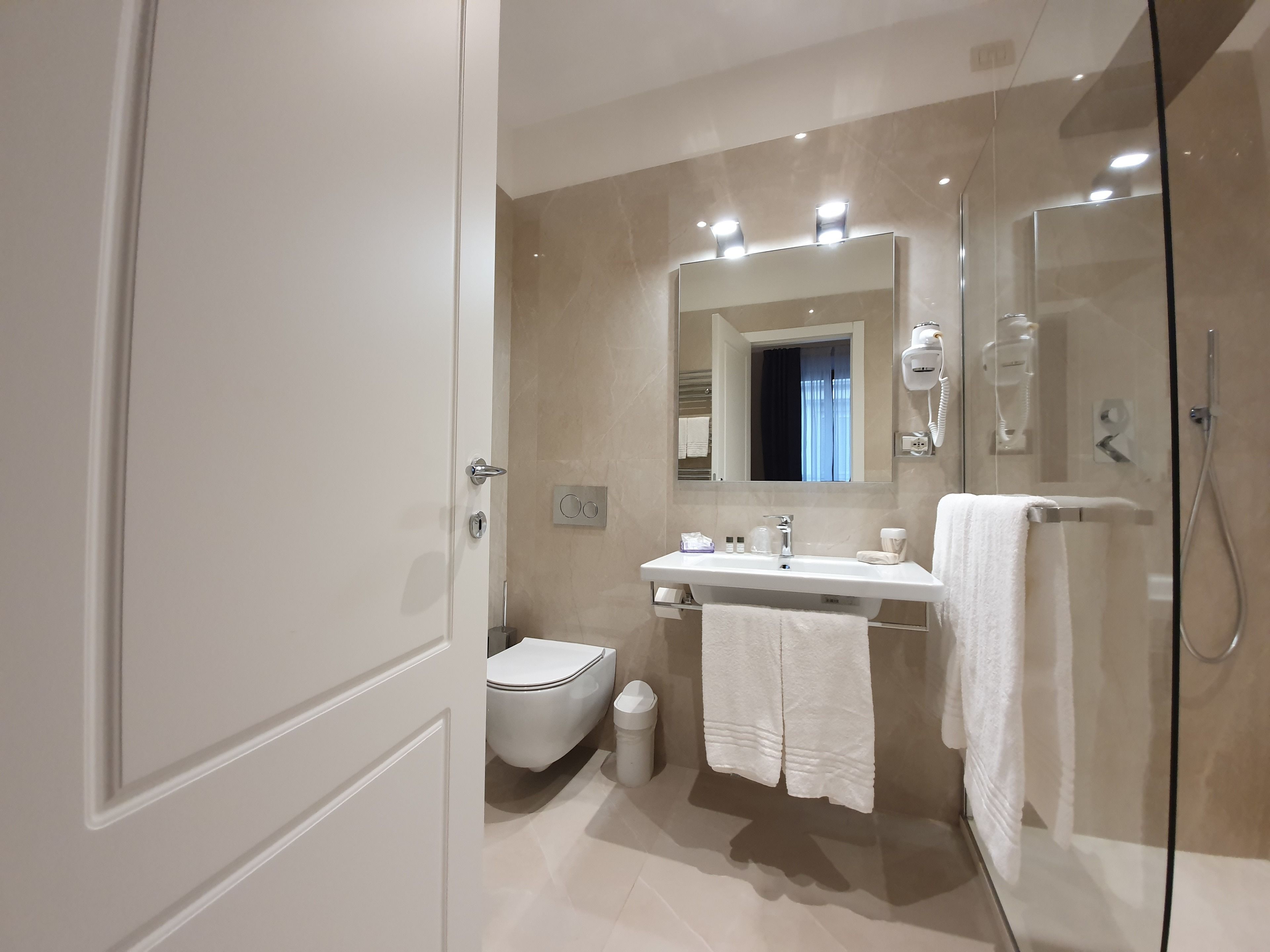 A modern bathroom with a glass shower enclosure, a white sink, and a toilet.