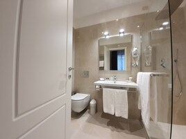 Un bagno moderno con cabina doccia in vetro, lavabo bianco e servizi igienici.