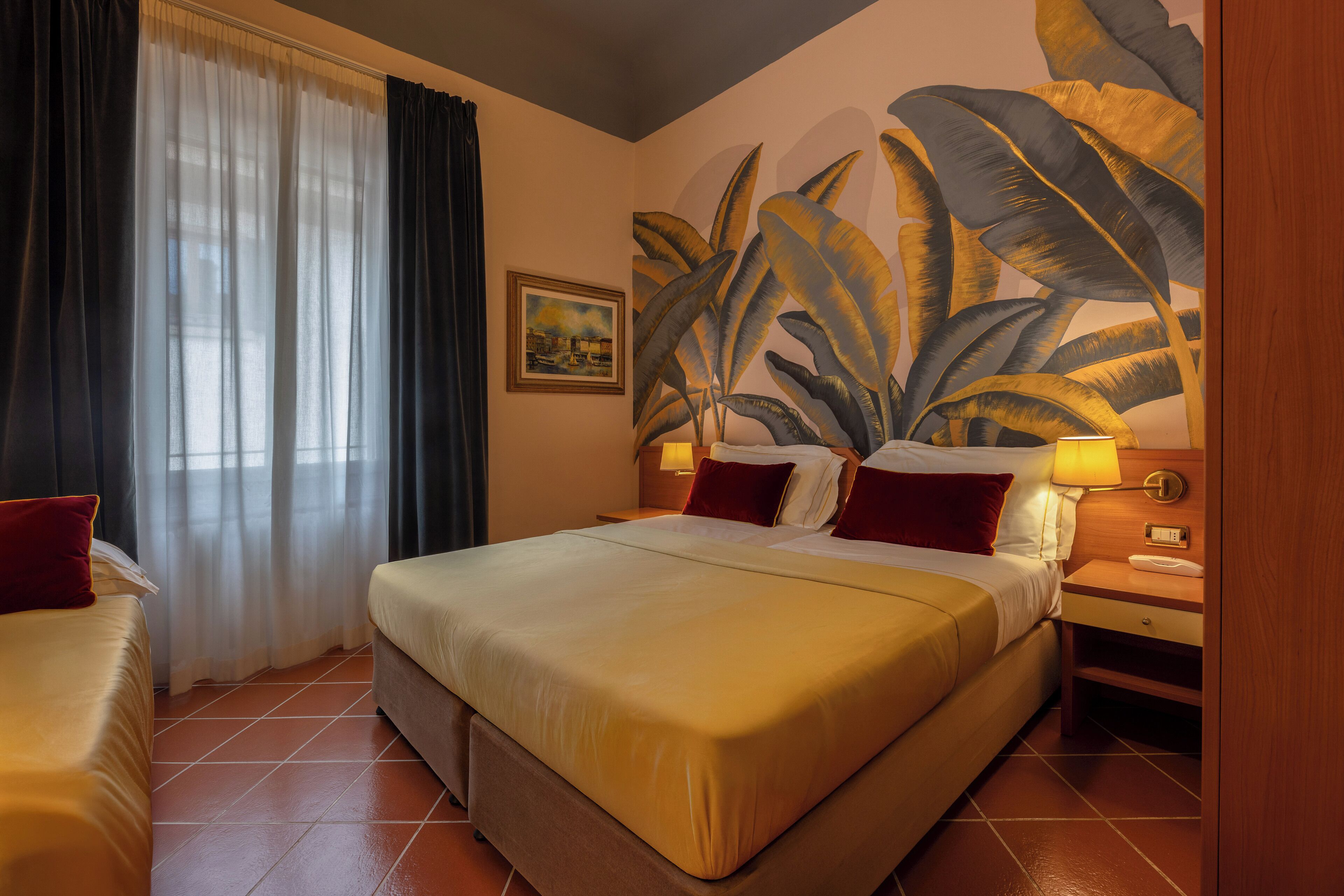 A hotel room with a large bed, a bedside table with a lamp, a painting on the wall, and a window with curtains.
