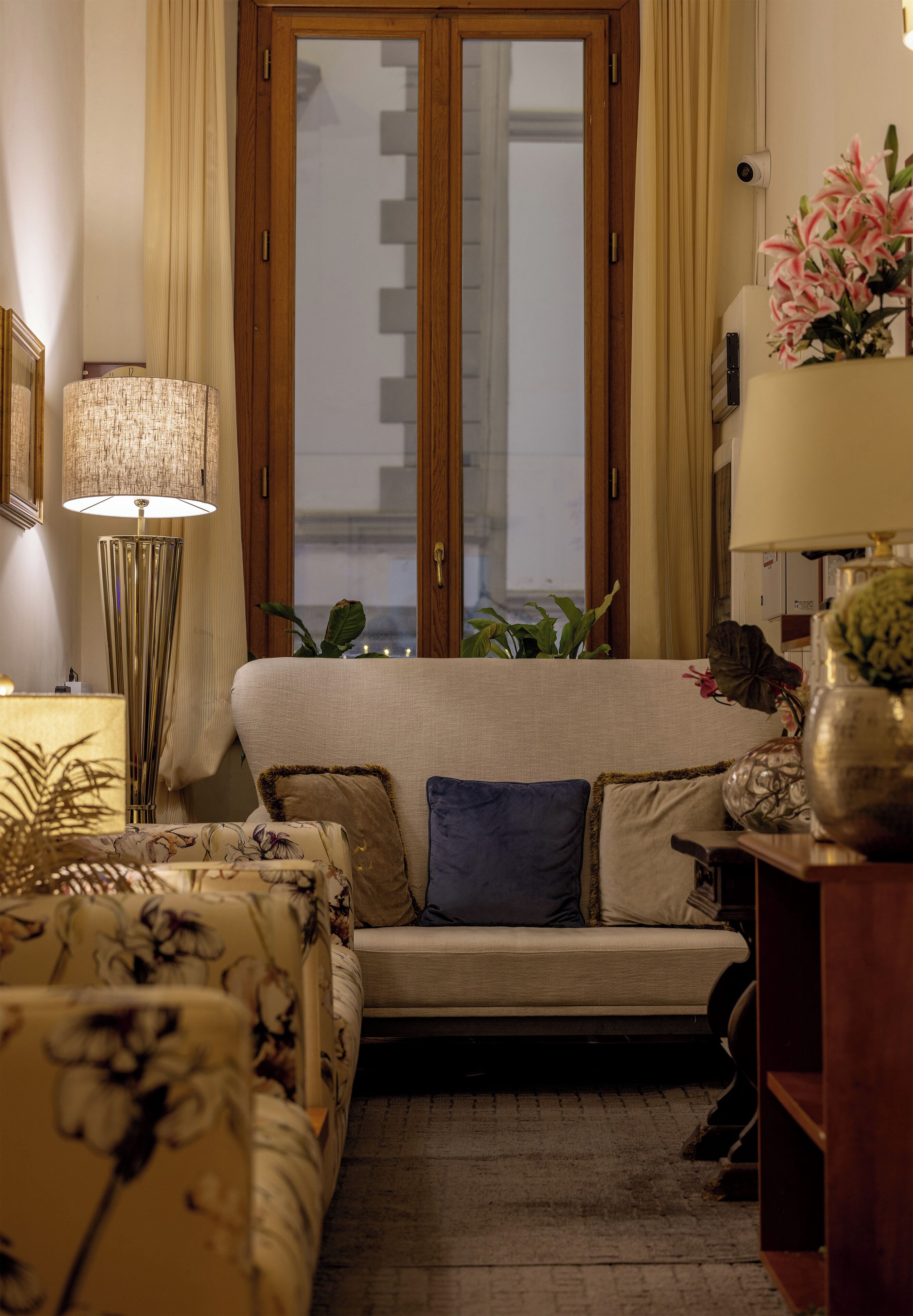 A cozy living room with a sofa, a side table, a lamp, and a window with curtains.