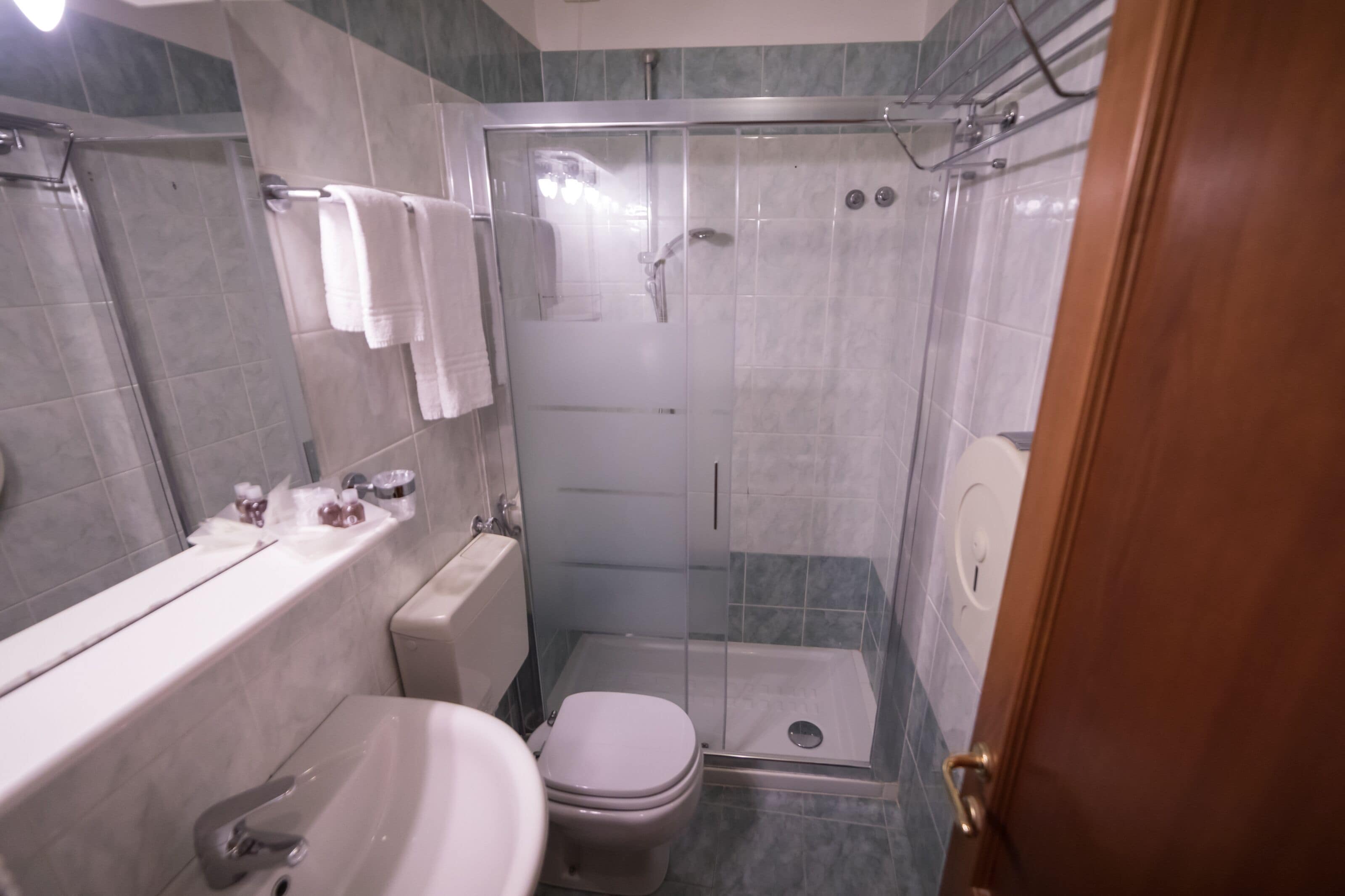 A bathroom with a glass-enclosed shower, a toilet, and a sink.
