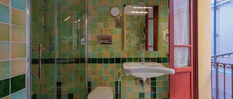 A bathroom with a glass shower enclosure, a toilet, and a sink.